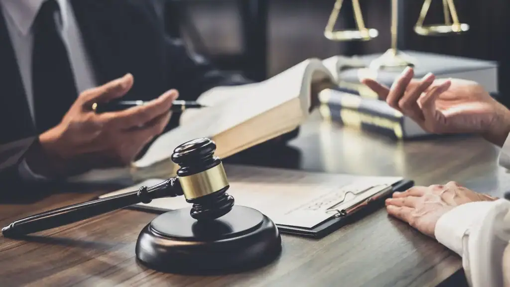 استشارة قانونية بين محامٍ وموكّلته أمام مطرقة قضائية وكتاب قانوني مفتوح